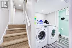 Carpeted staircase with white handrail, recessed lighting, and laundry area featuring front-loading washer and dryer - 