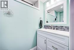 White vanity with integrated sink, mosaic tile backsplash, framed mirror, and wall-mounted light fixture - 