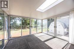 Sunroom with multiple sliding glass doors, a large skylight, and modular carpet flooring - 