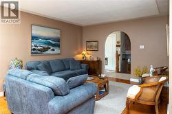 Arched doorway entry to an interior space, with wood-finish flooring, and a neutral wall color - 