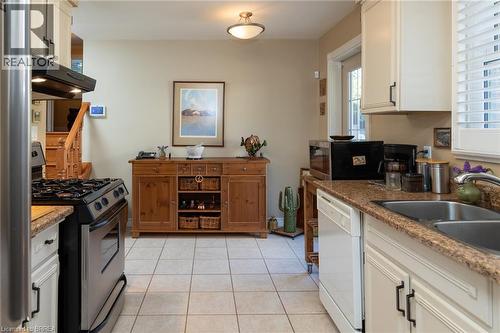 Kitchen featuring cream-painted cabinetry, a stainless steel gas range, a double basin sink, and tile flooring - 78 Berkley Crescent, Simcoe, ON 