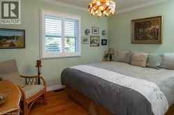 Hardwood flooring, crown molding, window with plantation shutters, ceiling-mounted stained glass light fixture, wall-mounted artwork - 