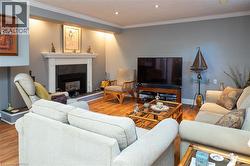 Hardwood flooring, recessed lighting, crown molding, fireplace with white mantel, and built-in shelving - 