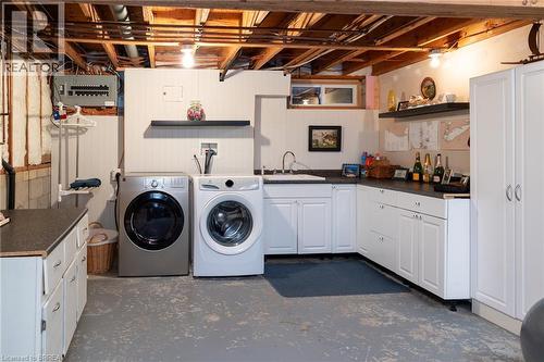 Utility room with white shaker cabinetry, dark countertops, a single basin sink, and a front-load washer and dryer - 78 Berkley Crescent, Simcoe, ON 