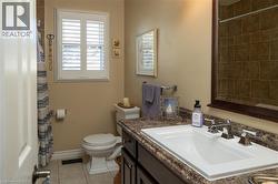 White plantation shutters, full vanity with integrated sink, chrome dual-handle faucet, dark wood-finish vanity cabinetry, and a walk-in shower with brown tile surround - 