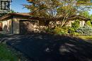 Brick exterior with a brown garage door, asphalt driveway, and established landscaping - 78 Berkley Crescent, Simcoe, ON 