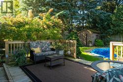 Expansive backyard featuring a wood deck, wood-slat fencing, mature trees, and an in-ground pool - 