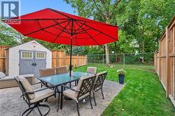 Patio with stamped concrete, expansive lawn, wood fencing, and a detached storage shed - 