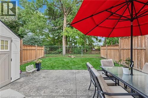 Stamped concrete patio with a detached storage shed, a manicured lawn, and wood privacy fencing - 332 Grand River Avenue, Brantford, ON 