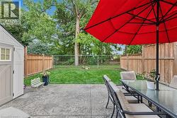 Stamped concrete patio with a detached storage shed, a manicured lawn, and wood privacy fencing - 