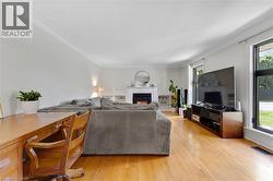 Hardwood flooring, crown molding, built-in fireplace with white mantel, white built-in shelving, and large windows - 