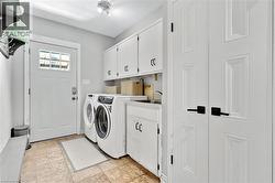 Utility area featuring white paneled cabinetry, front-load washer and dryer, and a built-in sink with a countertop - 