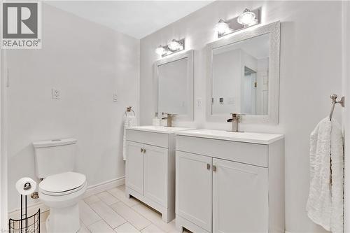 Dual white vanities with integrated sinks, framed mirrors, and matching wall-mounted light fixtures - 7 Shadywood Lane, Cambridge, ON 