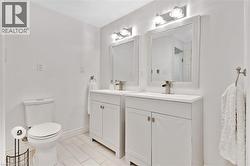 Dual white vanities with integrated sinks, framed mirrors, and matching wall-mounted light fixtures - 