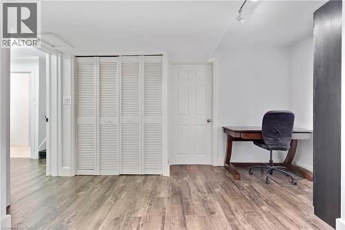 Wood-finish flooring with white louvered bifold closet doors and track lighting - 7 Shadywood Lane, Cambridge, ON 