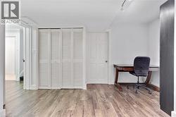 Wood-finish flooring with white louvered bifold closet doors and track lighting - 
