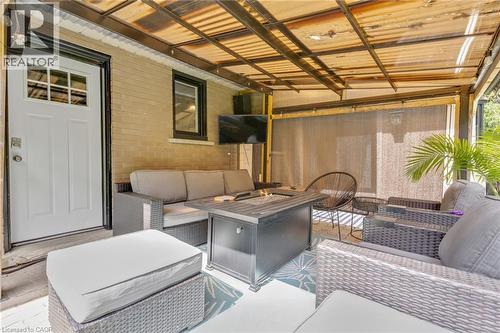 Covered outdoor patio featuring a brick wall, white exterior door with window panes, and a mounted outdoor light fixture - 7 Shadywood Lane, Cambridge, ON 