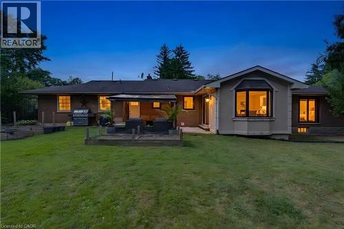 Expansive lawn with a bay window, brick and stucco exterior, and a rear patio - 7 Shadywood Lane, Cambridge, ON 