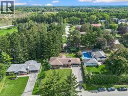 Aerial perspective showcasing multiple properties, an in-ground pool, and extensive surrounding greenery - 