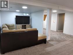 Finished basement recreation area featuring recessed lighting, neutral carpeting, and a built-in media console with ample storage - 