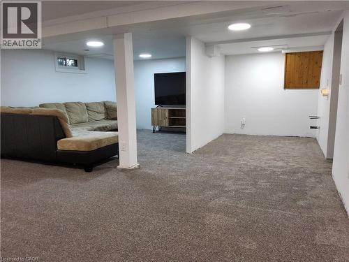 Expansive carpeted area with white painted walls, recessed ceiling lighting, and a white support column - 33 Lee Avenue, Simcoe, ON 