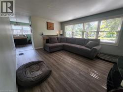Living area with wood-finish flooring, a large window, and a stone-clad feature wall - 