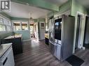 Spacious kitchen featuring stainless steel French-door refrigerator, wood-finish flooring throughout, soft-close cabinetry, and abundant natural light from multiple windows - 33 Lee Avenue, Simcoe, ON 