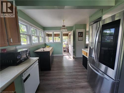 Kitchen featuring wood-finish flooring, white countertops, built-in cabinetry, and a black kitchen island - 33 Lee Avenue, Simcoe, ON 