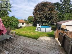 Expansive backyard featuring a wood deck, stone patio, and an above-ground pool - 