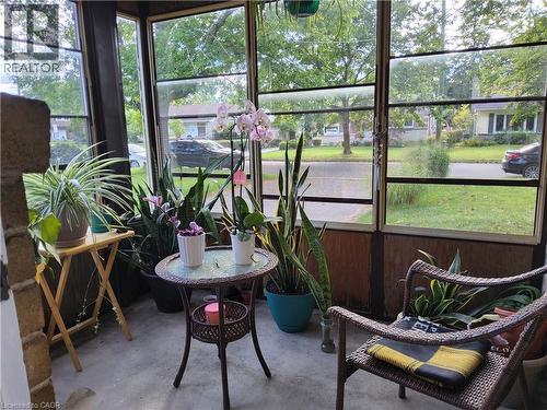 Enclosed porch featuring full-length windows, concrete flooring, and wood-paneled lower walls - 33 Lee Avenue, Simcoe, ON 