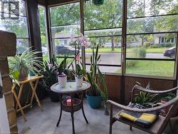 Enclosed porch featuring full-length windows, concrete flooring, and wood-paneled lower walls - 