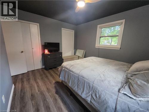 Wood-finish flooring with a ceiling fan, a window with white trim, and a white bi-fold closet - 33 Lee Avenue, Simcoe, ON 