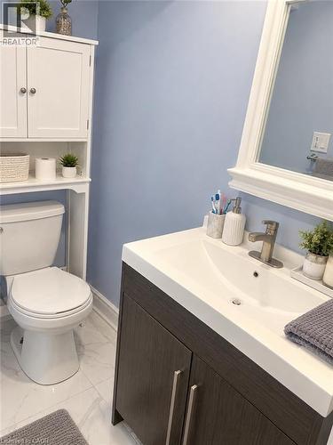 Vanity with a white integrated sink and brushed nickel faucet, wood-finish cabinetry, and a framed mirror - 73 Larkspur Crescent, Kitchener, ON 