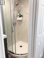 Corner shower enclosure with clear glass panels, a curved shower base, and a chrome shower head and fixtures - 