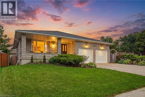 Stone facade residence featuring a covered front porch, two-car garage, and established landscaping - 76 Madeira Crescent, Cambridge, ON 