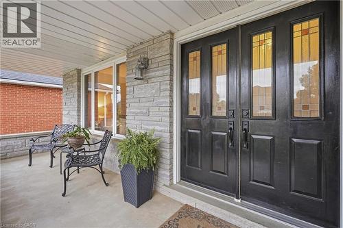 Double entry doors with decorative glass panels, stone facade, covered porch, and white framed windows - 76 Madeira Crescent, Cambridge, ON 
