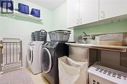Laundry area featuring white cabinetry, a stainless steel utility sink, wall-mounted faucet, and floating shelving - 