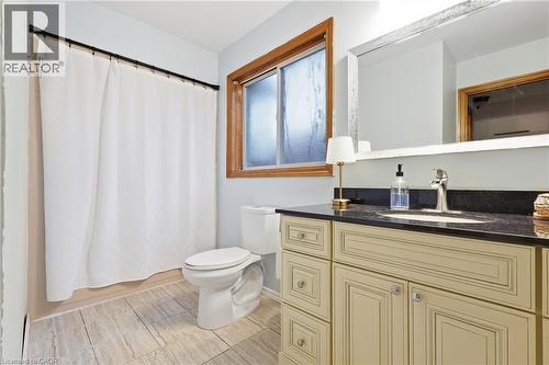 Recessed sink vanity with dark countertop, wood-framed window, and light-toned floor tiling - 76 Madeira Crescent, Cambridge, ON 