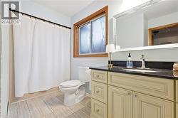 Recessed sink vanity with dark countertop, wood-framed window, and light-toned floor tiling - 