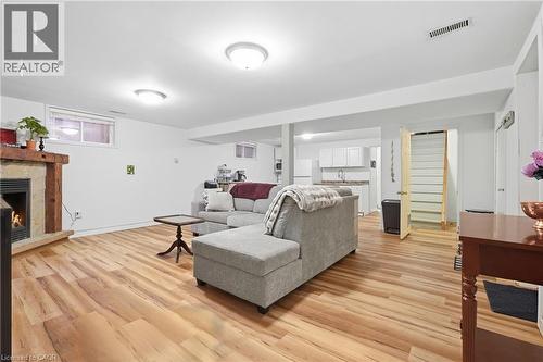 Wood-finish flooring throughout, featuring a stone-clad fireplace, built-in kitchen cabinetry, and recessed lighting - 76 Madeira Crescent, Cambridge, ON 