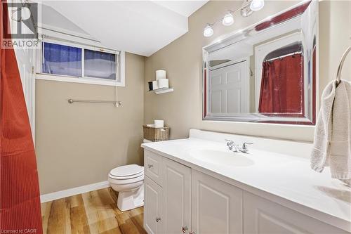 White vanity with an integrated sink, polished chrome faucet, framed mirror, and wood-finish flooring - 76 Madeira Crescent, Cambridge, ON 