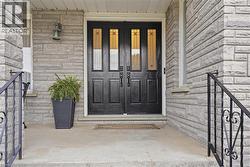 Double entry doors with decorative glass panels, stone veneer facade, and wrought iron handrails - 