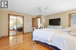 Hardwood flooring, mirrored closet doors, ceiling fan with integrated lighting, and neutral wall tones - 
