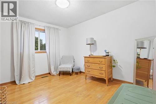 Hardwood flooring, window with wood trim, ceiling-mounted light fixture, white walls, and wood baseboards - 76 Madeira Crescent, Cambridge, ON 
