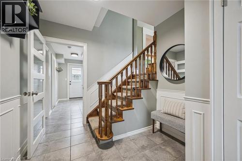 Tiled flooring, wood staircase with carpet runner, wainscoting, and a white paneled door with frosted glass inserts - 112 Margaret Avenue N, Waterloo, ON 