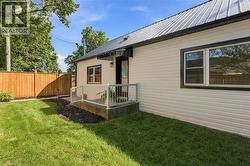 White horizontal siding with black trim windows, a metal roof, and a wooden privacy fence - 