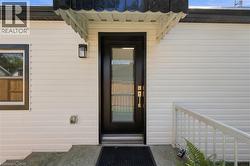 White horizontal siding with black trim, black entry door with clear glass panels, and an exterior wall lantern - 