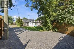 Gravel driveway with a wooden fence and lush perimeter landscaping - 