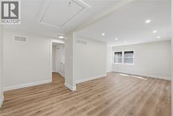 Recessed ceiling lighting, wood-finish flooring, white trim, and a window for natural illumination - 