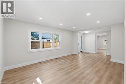 Recessed lighting, wood-finish flooring, white trim, and light gray walls - 
